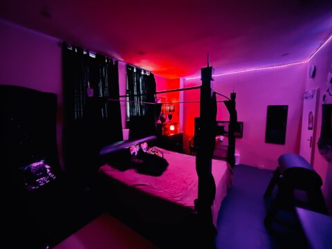 Ein Bett in einem Raum mit roten und violetten Lichtern.