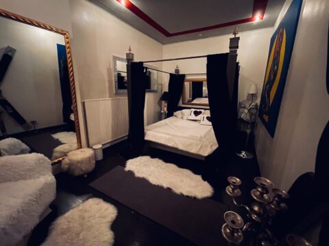 Ein schwarz-weißes Schlafzimmer mit einem Bett und einem Spiegel.