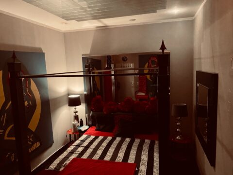 Ein schwarz-rot gestreiftes Bett in einem Zimmer.