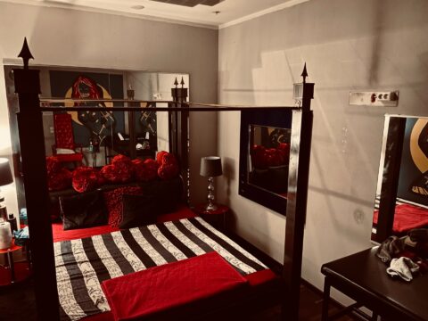 Ein Schlafzimmer mit einem schwarz-roten Himmelbett.
